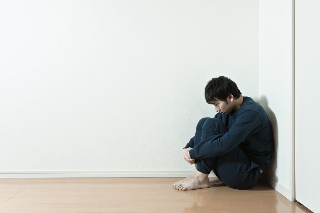 部屋で悩む男性[