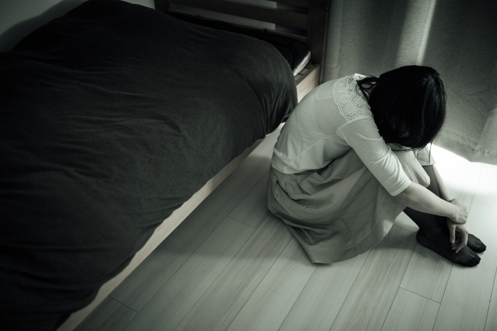 部屋でうずくまる女性。